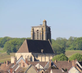 Le clocher de l'église St-Denis émerge au-dessus des toits de petites tuiles plates